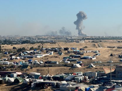 نازحون فلسطينيون في رفح جنوبي قطاع غزة بينما تتصاعد الأدخنة جراء الغارات الإسرائيلية على القطاع. 11 فبراير 2024 - Reuters