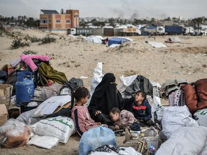 أسرة فلسطينية تستريح خلال رحلة نزوحها من مدينة رفح إلى وسط قطاع غزة. 13 فبراير 2024 - AFP