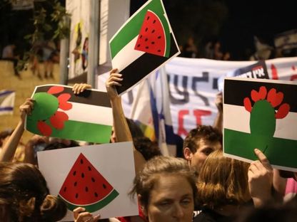 متظاهرون إسرائيليون يحملون لافتات بألوان العلم الفلسطيني وعليها صورة البطيخ أو كلمة “حرية” في القدس. 23 يوليو 2023 - AFP