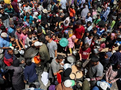 فلسطينيون يتجمعون لتلقي الطعام وسط أزمة جوع في مخيم النصيرات وسط قطاع غزة. 20 يوليو 2025 - REUTERS