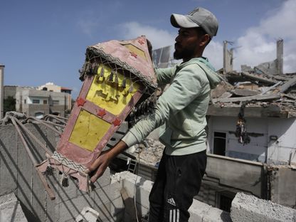 فلسطيني يحمل فانوساً  ليضعه فوق منزله المدمر في دير البلح. غزة. 6 مارس 2024 - AFP