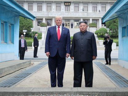الرئيس الأميركي دونالد ترمب والزعيم الكوري الشمالي كيم جونج أون يقفان عند خط ترسيم عسكري في المنطقة منزوعة السلاح (DMZ) التي تفصل بين الكوريتين في بانمونجوم. 30 يونيو 2019 - Reuters