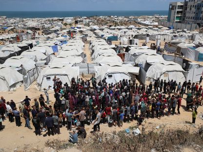 فلسطينيون ينتظرون الحصول على مساعدات بالقرب من الخيام التي لجأوا إليها في مدينة غزة. 28 مايو 2025 - REUTERS