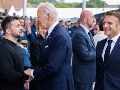 الرئيس الأمريكي جو بايدن يتحدث مع الرئيس الأوكراني فولوديمير زيلينسكي وإلى جانبهما الرئيس الفرنسي إيمانويل ماكرون في الذكرى الثمانين لإنزال نورماندي. 6 يونيو 2024 - AFP