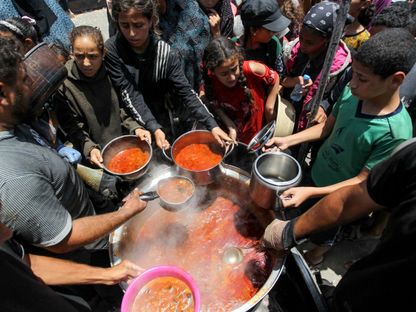 فلسطينيون ينتظرون الحصول على طعام يقدمه مطبخ خيري في خان يونس وسط نقص المساعدات واستمرار الحرب الإسرائيلية على غزة- 19 يونيو 2024 - Reuters