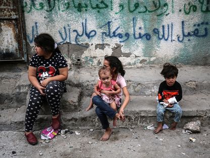 أطفال فلسطينيون يجلسون أمام أحد المنازل بمدينة غزة في ظل غارات إسرائيلية مستمرة. 9 أكتوبر 2023 - AFP
