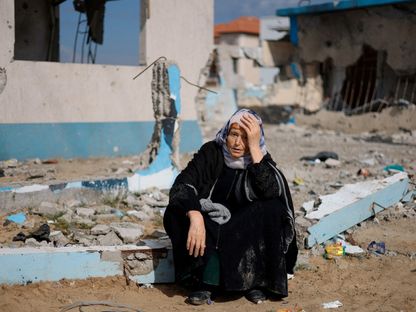 فلسطينية تجلس بجوار مبنى مدمر في رفح جنوب قطاع غزة. 15 فبراير 2024 - Reuters