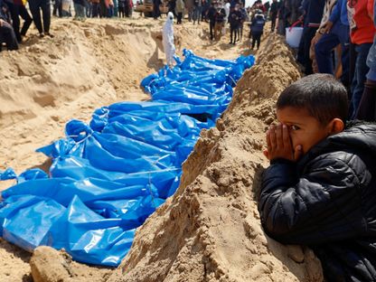 طفل فلسطيني يقف أمام مقبرة جماعية لفلسطينيين قتلوا في غارات إسرائيلية بمدينة رفح جنوب قطاع غزة. 7 مارس 2024 - REUTERS