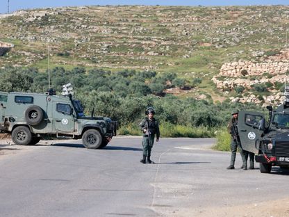 قوات الأمن الإسرائيلية تحرس نقطة تفتيش أثناء البحث عن مراهق إسرائيلي مفقود في قرية المغير بالقرب من رام الله في الضفة الغربية. 13 أبريل 2024 - AFP