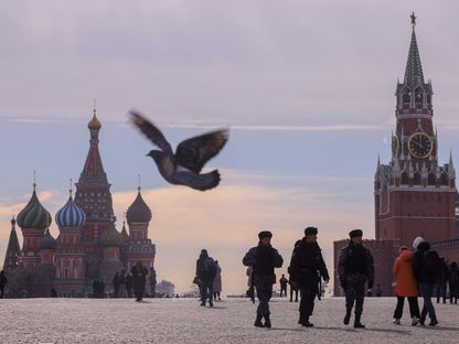 أشخاص وضباط روس يسيرون بالقرب من كاتدرائية القديس باسيل وبرج سباسكايا في الكرملين وسط موسكو. 20 مارس 2023 - REUTERS