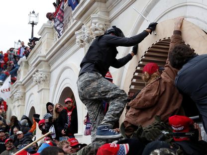 متظاهرون مؤيدون لترمب يتسلقون جدارا أثناء اقتحامهم مبنى الكابيتول الأميركي في واشنطن. 6 يناير 2021 - Reuters