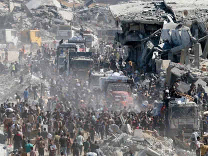 فلسطينيون يتجمعون في طريق وسط الأنقاض بخان يونس في محاولة للحصول على مساعدات إنسانية. غزة، 12 أكتوبر 2025 - Reuters