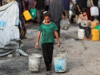 فتاة فلسطينية تحمل دلوين من الماء في ظل نقص المياه بمدينة غزة وسط الحرب الإسرائيلية على القطاع. 6 أغسطس 2025 - Reuters
