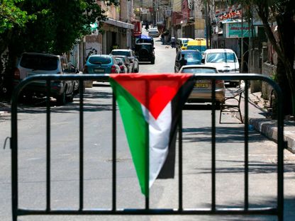 العلم الفلسطيني فوق حاجز عند نقطة تفتيش على مدخل مخيم عماري بالقرب من مدينة رام الله بالضفة الغربية. 24 يوليو 2020 - AFP