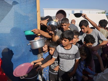 أطفال فلسطينيون في مخيم بخان يونس جنوب غزة ينتظرون دورهم للحصول على الطعام. 26 أكتوبر 2023 - AFP