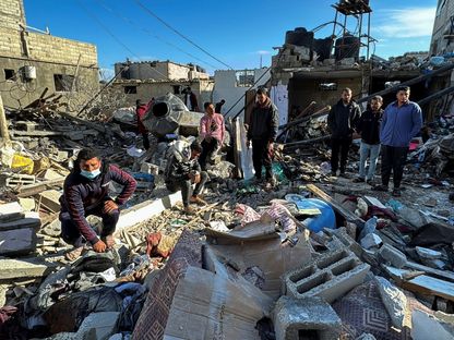 فلسطينيون يتفقدون موقع الدمار الذي خلفته غارة إسرائيلية في رفح جنوب قطاع غزة- 8 مارس 2024 - Reuters