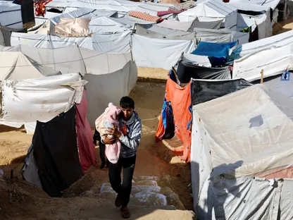 نازح فلسطيني يحمل طفلاً في مخيم بدير البلح، وسط قطاع غزة. 9 ديسمبر 22025 - Reuters