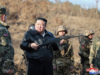 زعيم كوريا الشمالية كيم جونج أون يحمل بندقية أثناء تفقده قاعدة تدريب عسكرية رئيسية في المنطقة الغربية من البلاد. 7 مارس 2024 - REUTERS