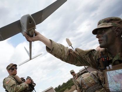 أحد عناصر الجيش الأميركي يمسك بطائرة تجسس مسيّرة. - Reuters