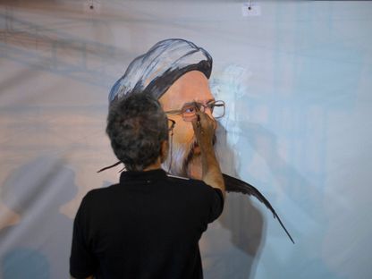 فنان إيراني يرسم لوحة للرئيس الراحل إبراهيم رئيسي خلال فعالية لتأبينه جنوبي طهران. 23 مايو 2024 - AFP