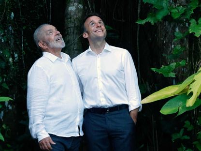 الرئيس البرازيلي لويس إيناسيو لولا دا سيلفا (يسار) والرئيس الفرنسي إيمانويل ماكرون يقفان لالتقاط صور تحت شجرة ضخمة عند وصولهما إلى جزيرة كومبو، أمام بيليم، ولاية بارا، البرازيل، في 26 مارس 2024- AFP - AFP