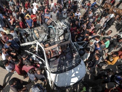 عشرات الفلسطينيين يتفحصون سيارة استهدفتها غارة إسرائيلية على دير البلح في قطاع غزة. 4 يونيو 2024 - AFP
