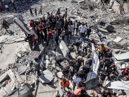 فلسطينيون يحاولون انتشال جثامين الضحايا والمصابين من بين الأنقاض في أعقاب غارة إسرائيلية على رفح جنوبي قطاع غزة. 20 مارس 2024 - AFP