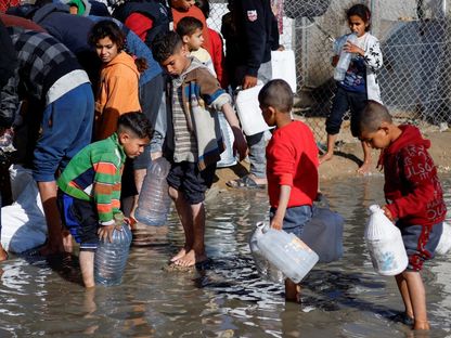 أطفال فلسطينيون يقفون وسط تجمع مياه داخل مخيم للاجئين في مدينة رفح، جنوب غزة. 18 يناير 2024 - Reuters