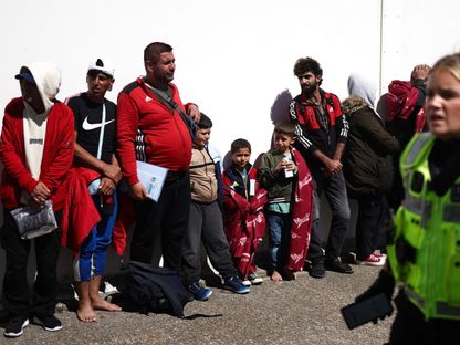 مهاجرون ينتظرون حافلة تقلهم لإتمام إجراءات في مدينة دونجينيس جنوبي شرقي بريطانيا. 16 أغسطس 2023 - AFP