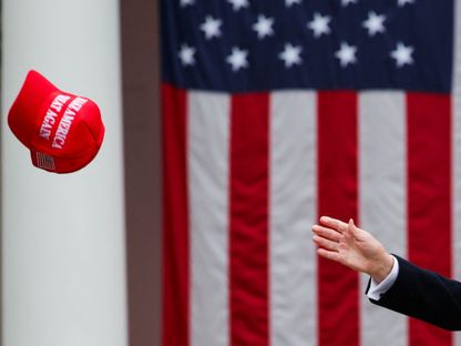 الرئيس الأميركي دونالد ترمب يحاول الإمسكاك بقبعة MAGA خلال مؤتمر صحافي بالبيت الأبيض. 2 أبريل 2025 - Reuters
