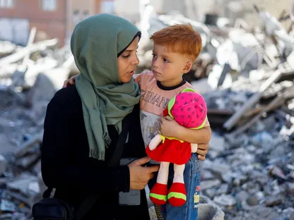 سيدة فلسطينية تحمل طفلها فوق أنقاض المنازل المدمرة جراء الغارات الإسرائيلية على خان يونس جنوب قطاع غزة. 11 سبتمبر 2025 - REUTERS