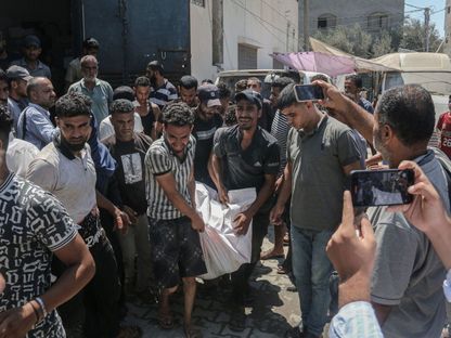 فلسطينيون ينقلون جثمان أحد الضحايا بالقرب من مستشفى "شهداء الأقصى" في أعقاب غارة إسرائيلية على دير البلح في قطاع غزة. 20 أغسطس 2024 - Bloomberg