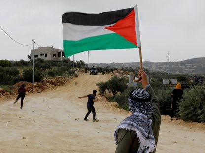 متظاهر يحمل العلم الفلسطيني خلال اشتباكات مع القوات الإسرائيلية في نابلس بالضفة الغربية. 10 أبريل 2023 - REUTERS