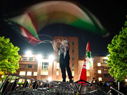 طالب يلوح بالعلم الفلسطيني خلال الاحتجاجات الداعمة للفلسطينيين في ساحة جامعة جورج واشنطن. 29 أبريل 2024 - AFP