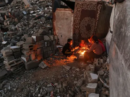 أطفال فلسطينيون يجلسون أمام النار للتدفئة في خان يونس بجنوب قطاع غزة. 25 نوفمبر 2025 - REUTERS