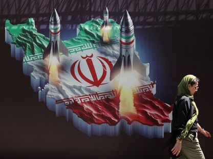 سيدة تسير أمام لافتة في العاصمة طهران تُجسد إطلاق صواريخ إيرانية نحو إسرائيل. 19 أبريل 2024 - Reuters