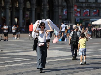 امرأة تحمي نفسها من حرارة الشمس باستخدام قميص في ميلانو بإيطاليا. 21 أغسطس 2023 - Reuters