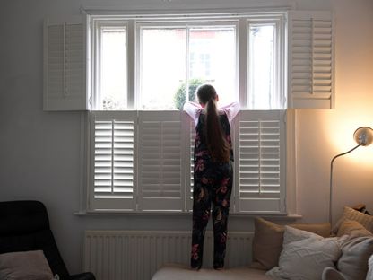 الطفلة إيف البالغة من العمر تسع سنوات تنظر بقلق من النافذة الأمامية في المنزل خلال وباء فيروس كورونا- بريطانيا في 17 مارس 2020. - Reuters