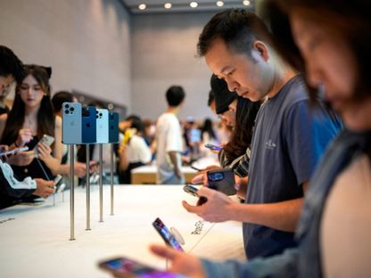 أشخاص يفصحون أجهزة آيفون 15 داخل أحد متاجر شركة أبل في شنغهاي بالصين. 22 سبتمبر 2023 - Reuters