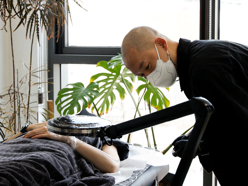 رسام الوشم كيم دو يون يحضر أحد العملاء في استوديو الوشم الخاص به في سيول ، كوريا الجنوبية ، 15 فبراير 2022. - REUTERS