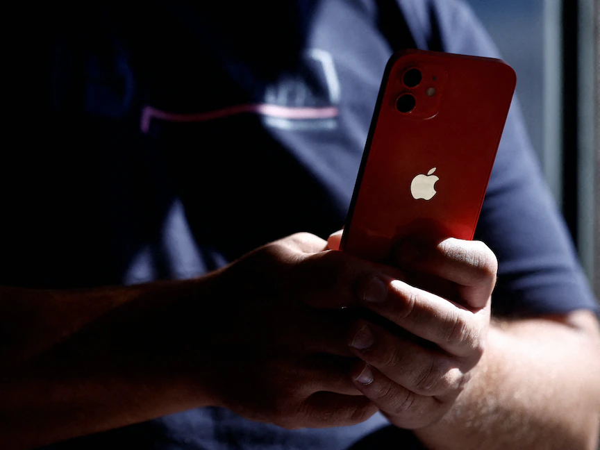 رجل يحمل هاتف "آيفون 12" بمتجر للهواتف في مدينة نانت الفرنسية. 13 سبتمبر 2023 - REUTERS