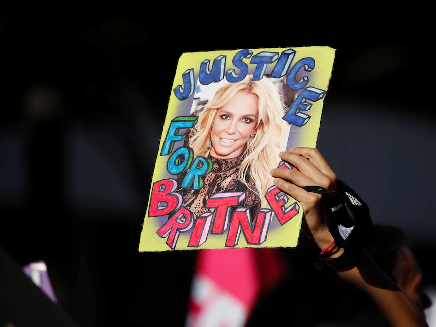 مناصرة للمغنية بريتني سبيرز تحمل صورتها مع عبارة "العدالة لبريتني" خلال الاحتفالات بإنهاء الوصاية عليها خارج محكمة ستانلي موسك في لوس أنجلوس، كاليفورنيا، الولايات المتحدة- 12 نوفمبر 2021 - REUTERS