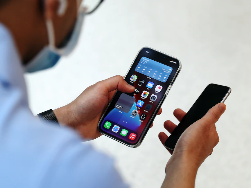 مستخدم يحمل هاتف "آيفون 12" في أحد متاجر "أبل" في أستراليا - Bloomberg