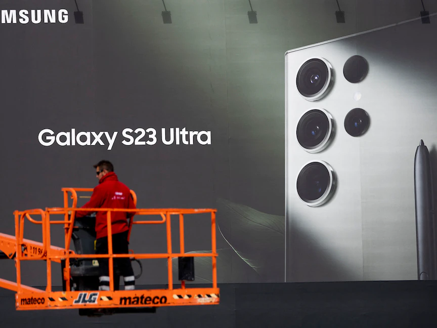 عامل يثبت لوحة إعلانية لشركة سامسونج خارج مركز "فيرا برشلونة" للمعارض مكان انعقاد "المؤتمر العالمي للجوال" (MWC) في برشلونة. 22 فبراير 2023 - AFP