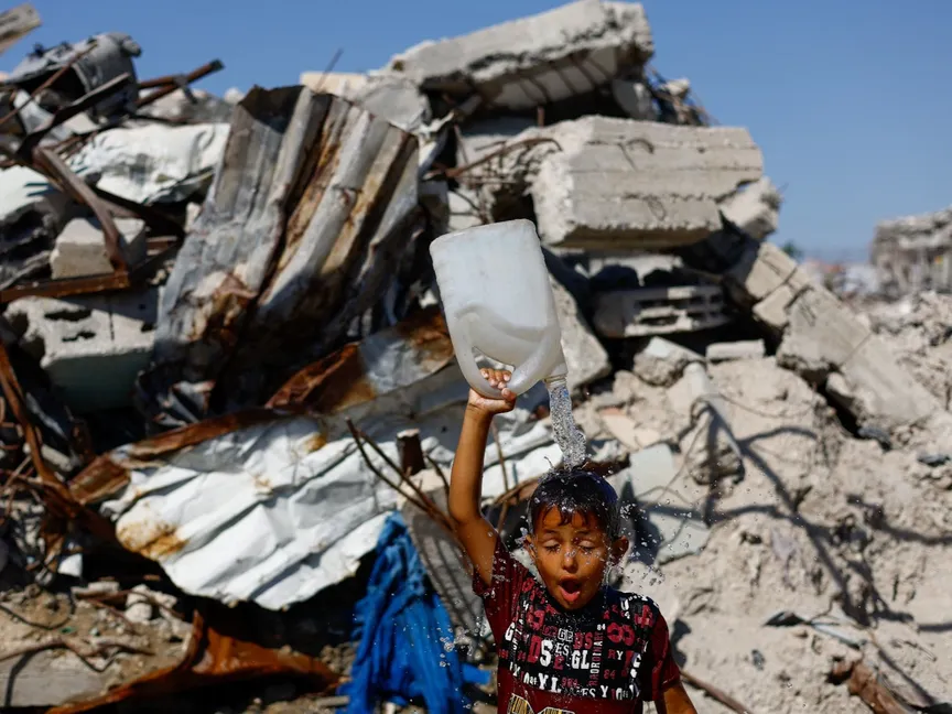 شاب فلسطيني يسكب الماء من حاوية بلاستيكية فوق رأسه وسط أنقاض مبانٍ دمرتها الحرب، في مخيم جباليا شمال قطاع غزة. 5 أغسطس2026 - Reuters
