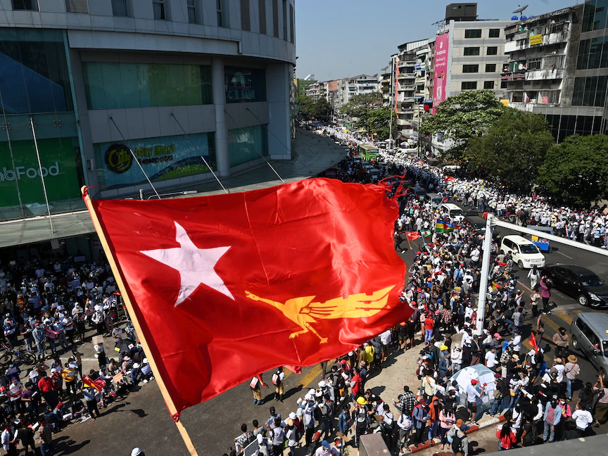 علم حزب الرابطة الوطنية من أجل الديمقراطية يرفرف فوق متظاهرين في يانغون، 10 فبراير 2021 - AFP