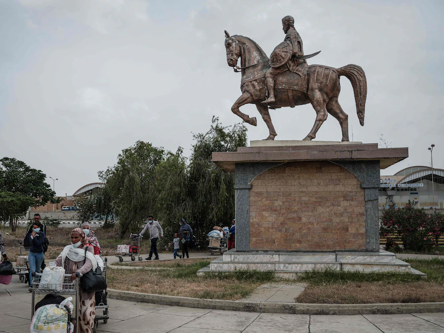 يسيرون قرب تمثال لألولا آبا نيغا وهو جنرال إثيوبي من تيغراي في ميكيلي عاصمة الإقليم - 25 يونيو 2021 - AFP