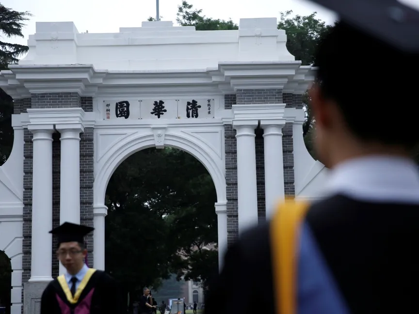 طلاب جامعيون يلتقطون صوراً عند بوابة قديمة لجامعة تسينجهوا في بكين، الصين، 23 يونيو 2020. - REUTERS