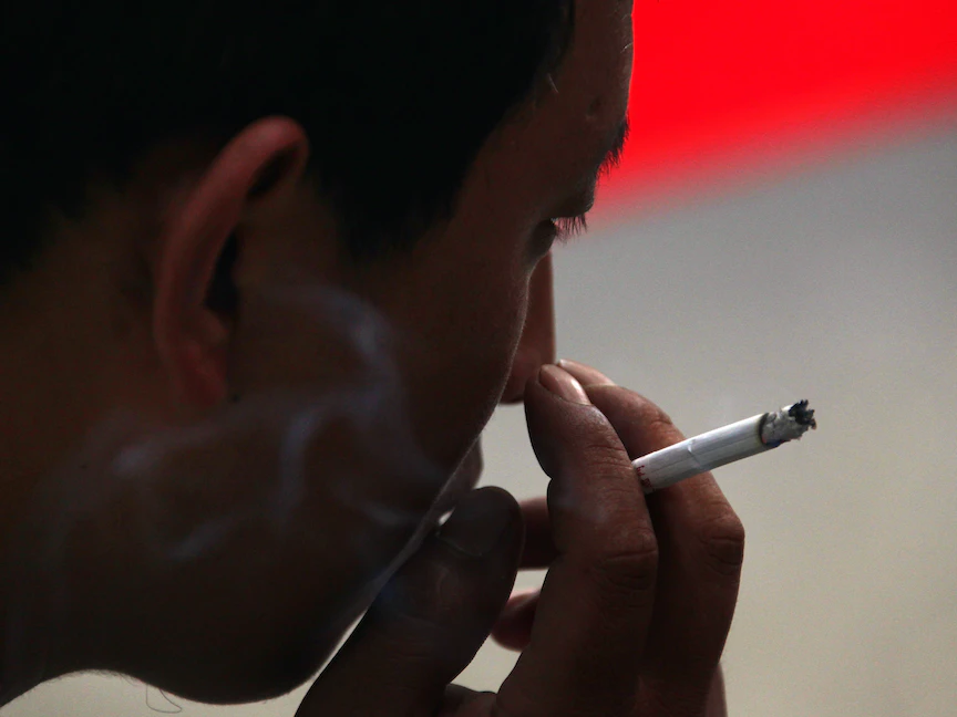 رجل يدخن سيجارة بينما يجلس في زقاق صغير وسط بكين، الصين- 18 أغسطس 2010 - REUTERS