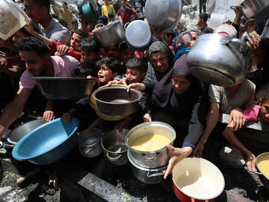 فلسطينيون ينتظرون الحصول على طعام من مطبخ خيري في جباليا. شمال قطاع غزة. 19 مايو 2025 - Reuters